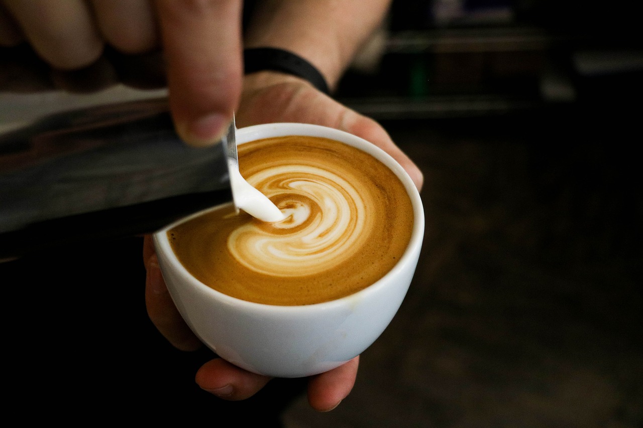 Kellner erstellt eine Figur im Milchschaum des Kaffee's