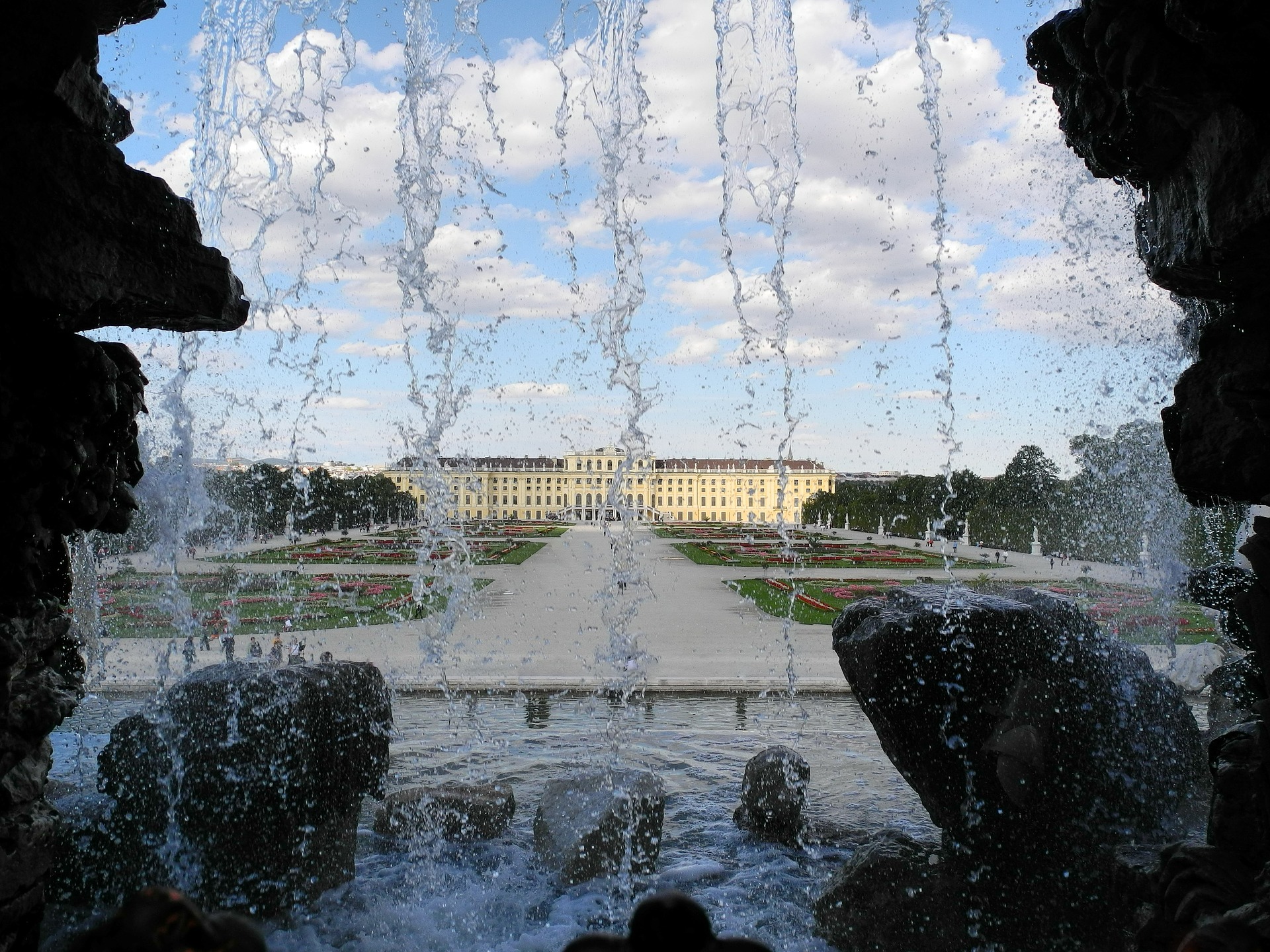 Blick durch das herunterfließende Wasser des Neptunbrunnens auf das Schloss Schönbrunn