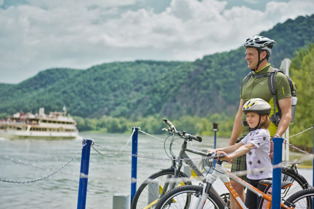Familie beim Radfahren auf dem Donauradweg mit Blick auf ein Schiff