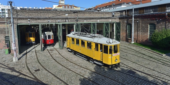 historische Straßenbahn fährt aus Gebäude raus.