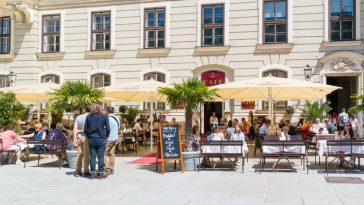 people on outdoor terrace of hofburg cafe in inner castle court in der burg in downtown vienna, austria