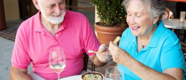senior couple on a date enjoys an artichoke dip appetizer