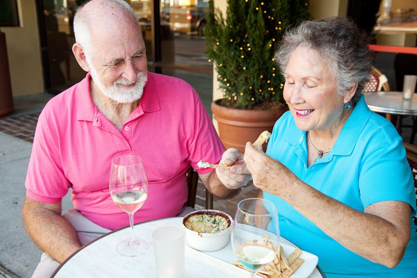 senior couple on a date enjoys an artichoke dip appetizer