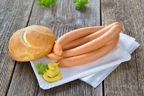four wieners with a fresh roll and spicy mustard on a paper plate