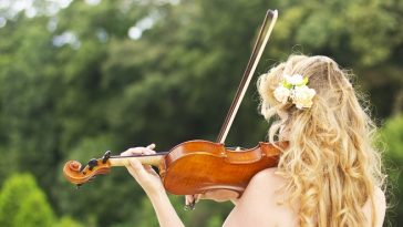 Beautiful smiling girl playing on the violin outdoors.