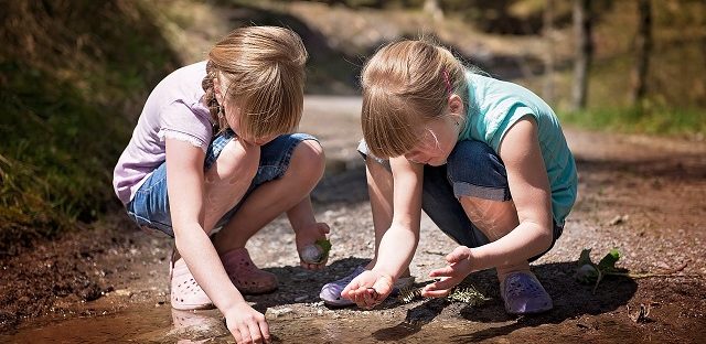 zwei Mädchen spielen mit Wasserlacke