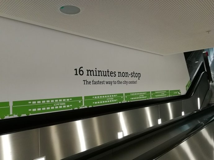 ein Schriftzug betreffend der Dauer der Fahrt in die Innenstadt, zu sehen entlang einer Rolltreppe.