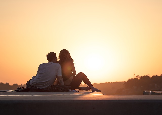 ein Paar sitzt auf einem Dach und genießt den Sonnenaufgang