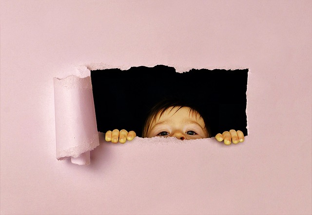 Kind sieht durch eine kleine Öffnung durch ein Blatt Papier