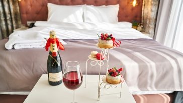 Blick auf ein wunderschönes Bett, im Vordergrund eine Flasche Champagner